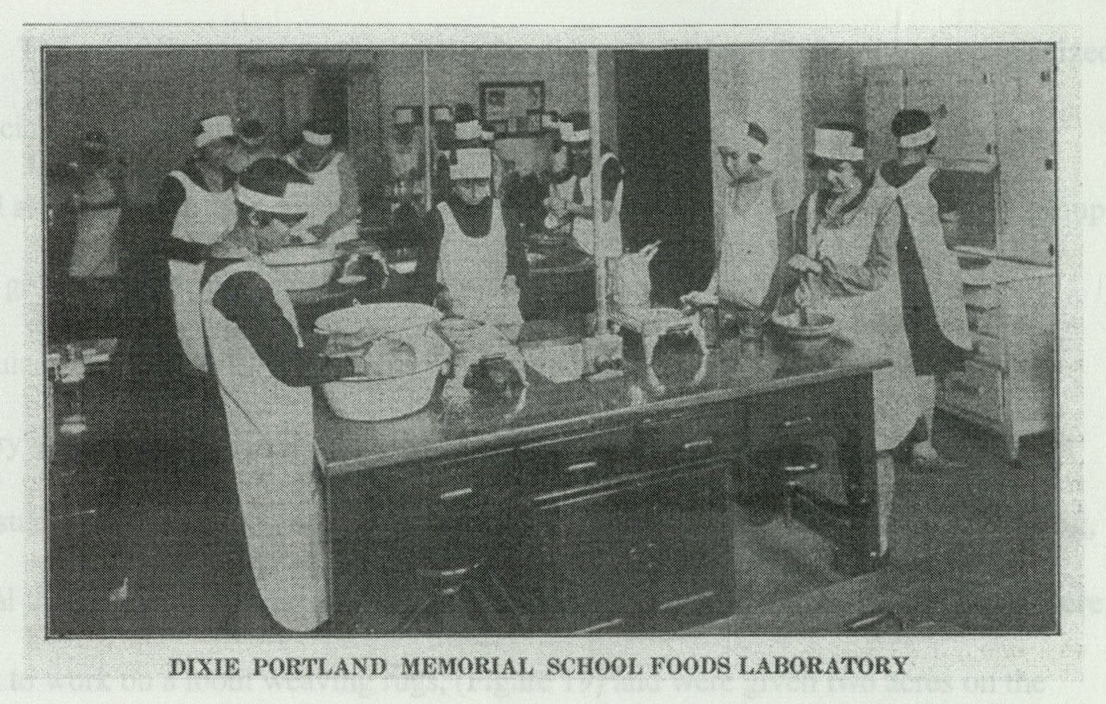 Students and teacher working in the foods laboratory classroom, with ranges and prep tables arrayed in rows