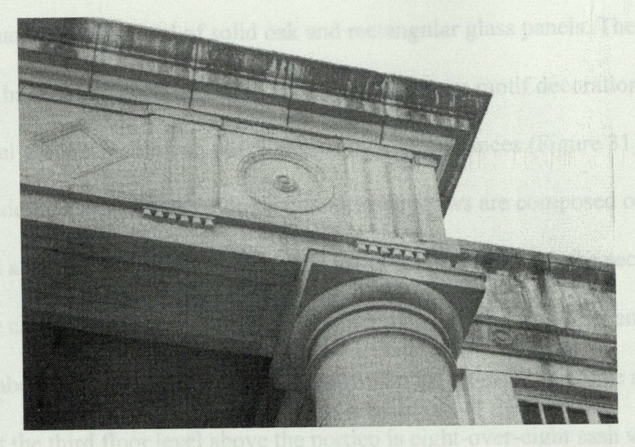 Close-up of the left corner of the portico entablature showing alternating diamond and bulls-eye motifs along the frieze