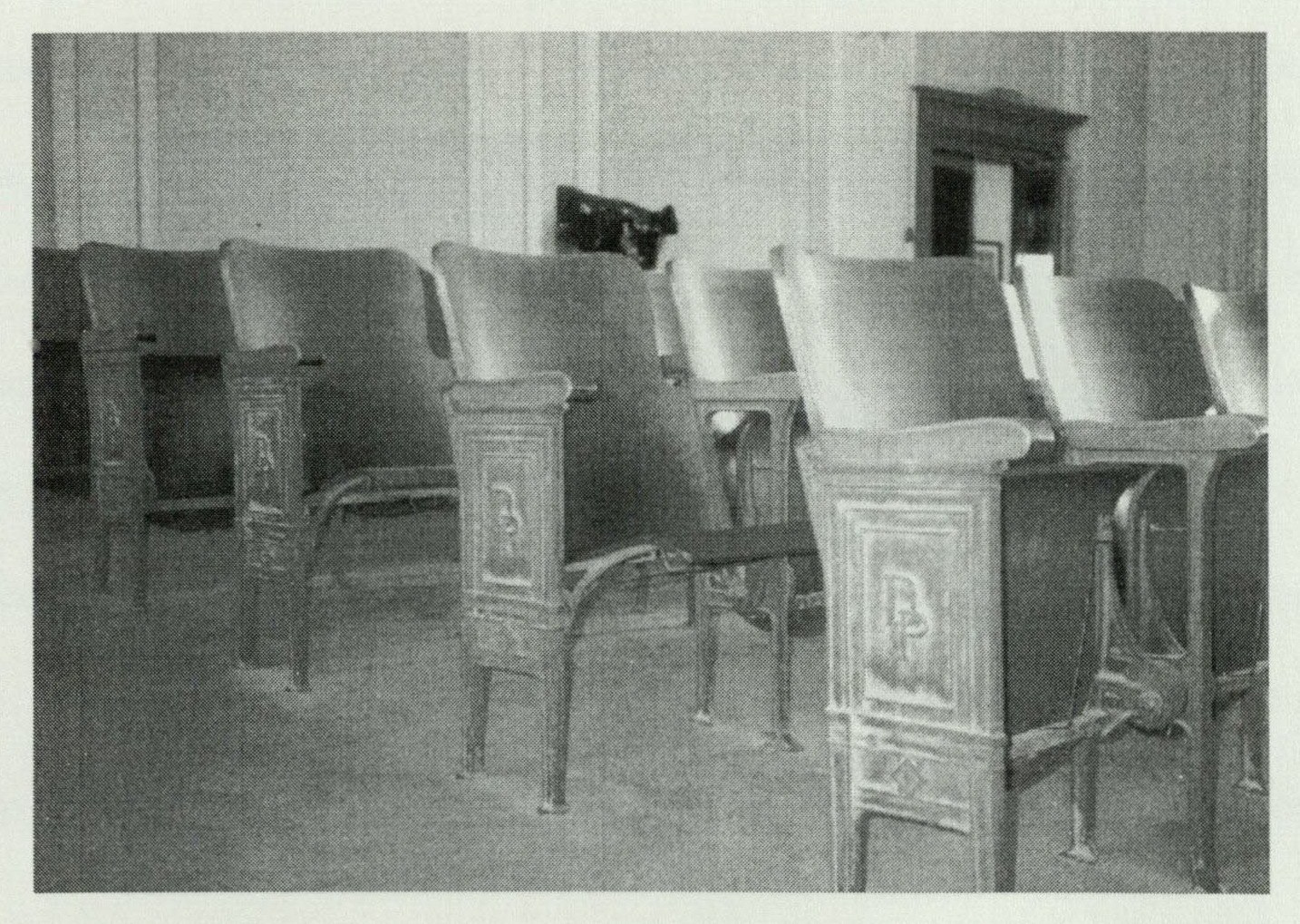 Close-up of auditorium theater seats with cast iron aisle enclosures embossed with the letters D and P for Dixie Portland