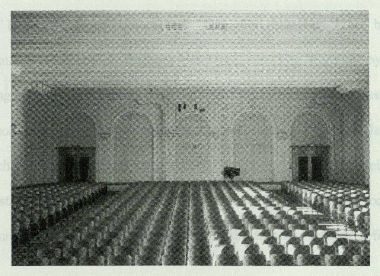 View from the stage toward the rear of the auditorium, showing rows of walnut seats and the balcony
